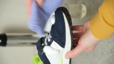 Şişedeki temizlik köpüğünü çocukların mavi kumaş ayakkabılarına sürüyorum. Ayakkabılara dikkat et, tozdan ve pislikten arındır..