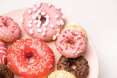Beyaz arka planda birçok farklı donut, farklı boyutlarda pembe, beyaz ve çikolatalı çörekler..