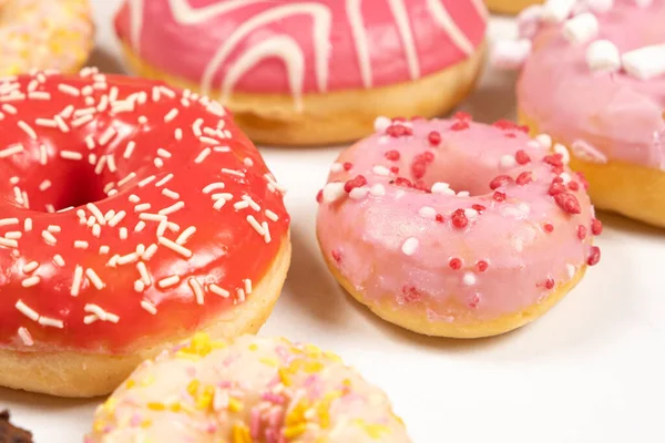 Donuts with red and pink glaze, side view. Lots of donuts, sweet and delicious food.