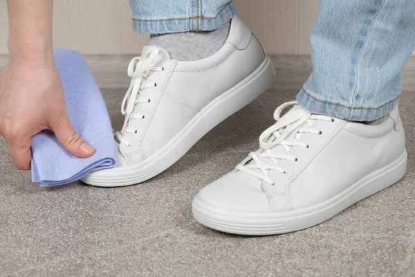 白い靴のクリーニング スニーカーの世話 女性はほこりや汚れからぬれた布で彼女の革の靴を拭く — ストック写真