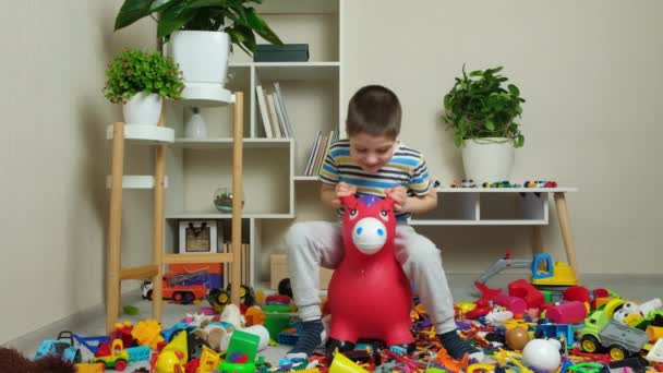 Mały Letni Chłopiec Skacze Nadmuchiwanej Zabawce Osła Pokoju Dziecięcym Pośród — Wideo stockowe