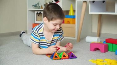 5 yaşında sevimli bir çocuk, manyetik bir inşaat setiyle figürler yaratıyor. Bir anaokulunun ilgi ve hayal gücünün gelişimi.