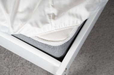 White satin sheet on an elastic band on the mattress. Bed linen on the bed.