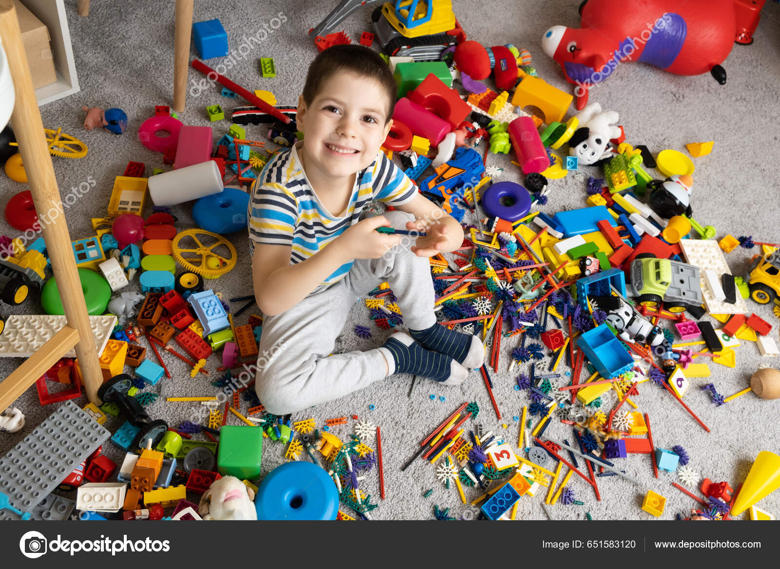 Retrato de un niño de 5 años contra el fondo de juguetes dispersos