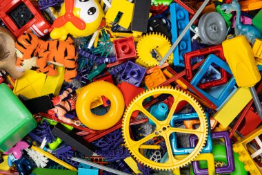 Çocuk odasında bir sürü oyuncak var. Tasarımcılardan bir sürü plastik renkli parça. Oyuncaklar, heykelcikler ve küpler için yedek parça.