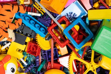 Çocuk odasında bir sürü oyuncak var. Tasarımcılardan bir sürü plastik renkli parça. Oyuncaklar, heykelcikler ve küpler için yedek parça.