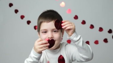 Sevimli küçük anaokulu çocuğu sevgililer gününde kalp şeklinde bir çelenkle oynuyor..