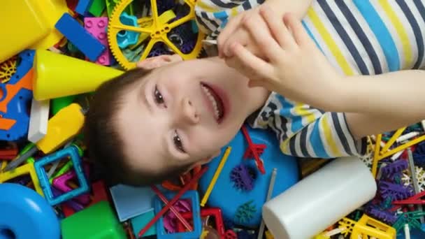 散在するおもちゃの背景に5歳の少年の肖像画 幸せな子供時代 おもちゃの豊富さ — ストック動画