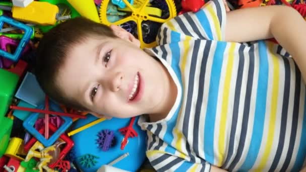 Przedszkolak Leży Podłodze Wśród Zabawek Wyciąga Ręce Macha Nimi Szczęśliwego — Wideo stockowe
