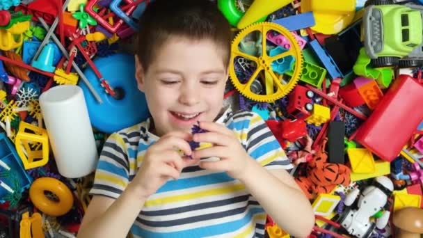 Симпатичный Маленький Мальчик Играет Игрушками Лежащими Среди Красочных Игрушек Полу — стоковое видео