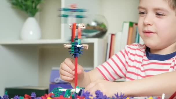 一个小男孩和一个建筑商一起玩 用齿轮和手杖创造人物形象 发展儿童的逻辑和思维 — 图库视频影像