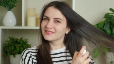 Uzun saçlı esmer bir kadın saçına tonik sıkar.