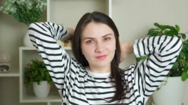 Esmer kadın uzun düz saçlarını doğal kahverengi renginde tarıyor ve kameraya bakıyor.