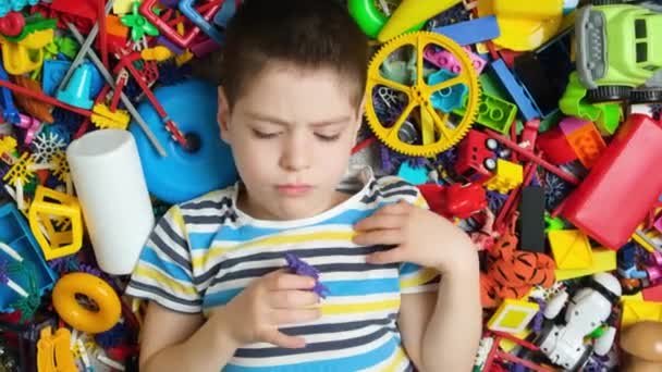 Сумний Ображений Маленький Хлопчик Викидає Іграшку Лежить Серед Різноманітних Іграшок — стокове відео