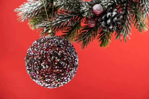 Λαμπερή Ροζ Μπάλα Ένα Χιονισμένο Κλαδί Χριστουγεννιάτικου Δέντρου Κόκκινο Φόντο — Φωτογραφία Αρχείου