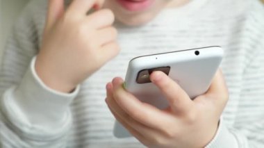 Bir çocuk akıllı telefon kullanır, parmağını ekrana bastırır, ellerini kapatır..
