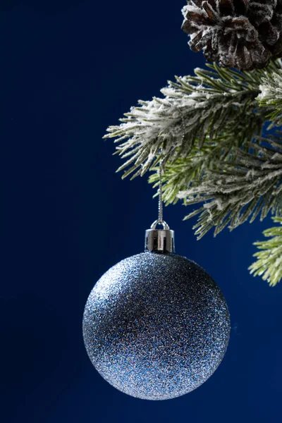 Μπλε Γυαλιστερή Μπάλα Ένα Χιονισμένο Κλαδί Χριστουγεννιάτικου Δέντρου Μπλε Φόντο — Φωτογραφία Αρχείου