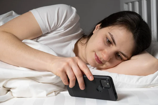 Woman Lies Bed Reads News Watches Something Smartphone Going Bed — Foto de Stock