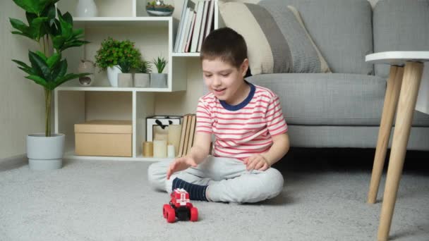 可愛いです5歳の男の子遊びますともにおもちゃのマシンでザカウチの近くに家に座って — ストック動画