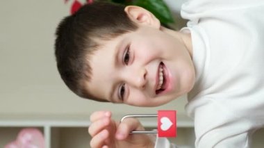 Sevimli 5-6 yaşlarında bir çocuk elinde bir kilit tutar ve ona bakıp gülümser ve konuşur.