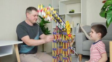 Baba ve oğul büyük bir elektrik binasıyla oynuyorlar. Hareket eden bir inşaatçı..