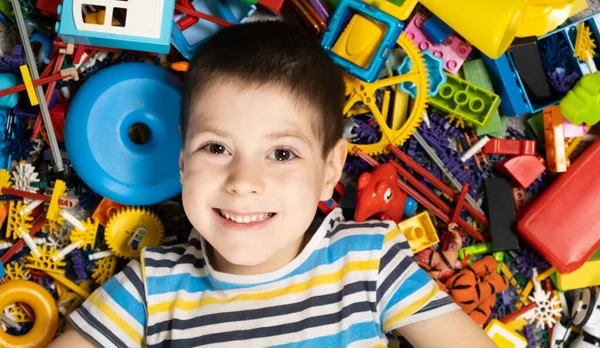 stock image Portrait of a 5-year-old boy against the background of scattered toys. Happy childhood, abundance of toys.