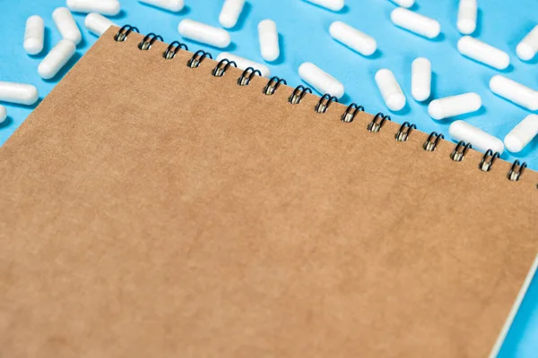 stock image Medical notepad with pills on a blue background, space for text.