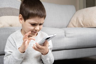 Anaokulundan bir çocuk akıllı telefon kullanıyor, telefonunda oyunlar oynuyor, mesaj atmak için yer arıyor..