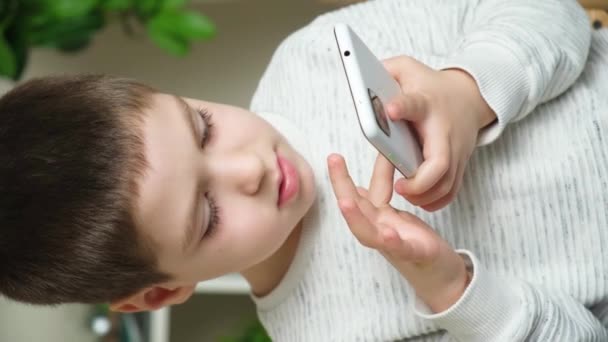 就学前の少年は スマートフォンでゲームをプレイし 画面上で指を実行し 話します — ストック動画