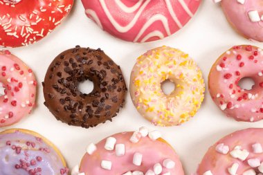 Beyaz arka planda birçok farklı donut, farklı boyutlarda pembe, beyaz ve çikolatalı çörekler..