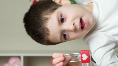 Sevimli 5-6 yaşlarında bir çocuk elinde bir kilit tutar ve ona bakıp gülümser ve konuşur.