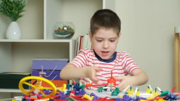 一个小男孩和一个建筑商一起玩 用齿轮和手杖创造人物形象 发展儿童的逻辑和思维 — 图库视频影像