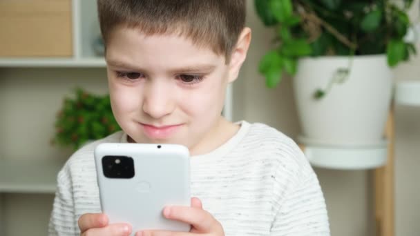 Ein Jähriger Junge Sieht Auf Seinem Smartphone Zeichentrickfilme Blickt Auf — Stockvideo