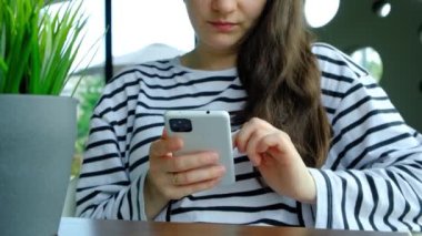 Esmer kadın akıllı telefon kullanıyor, bir kafede otururken sarkıyor.