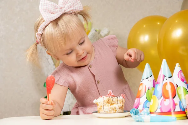 金发碧眼的小女孩 两条马尾辫 头戴蝴蝶结 生日那天用勺子和手吃蛋糕 — 图库照片