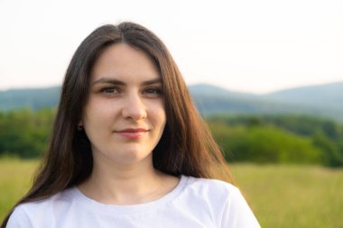 Otuz yaşında düşünceli esmer bir kadının portresi. Yazın doğada duruyor. Tarlada duruyor..