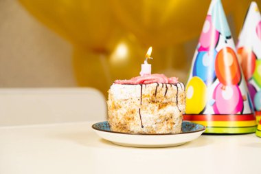 Küçük bir dilim pasta ve yanan bir doğum günü mumu.