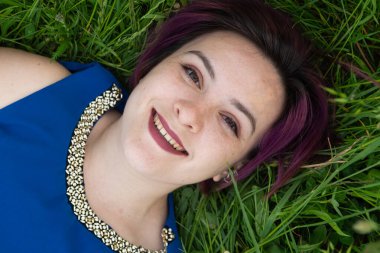 Mutlu genç kadın yazın çimenlerde yatıyor..