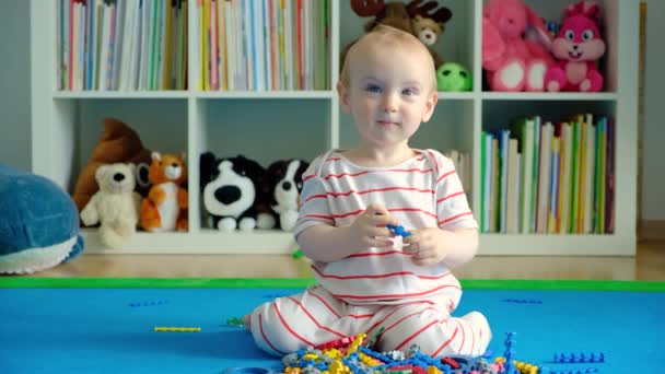 一个一岁大的婴儿坐在地毯上 在家里和一位设计师玩耍 — 图库视频影像