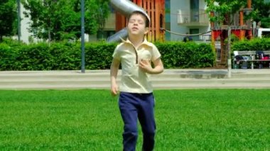5 yaşında bir çocuk parkta çimenlerde koşuyor. Ağır çekimde..