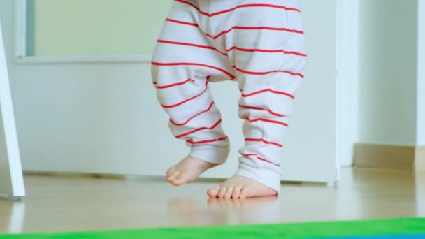 Ноги Ходьба Годовалого Ребенка Ребенок Полосатых Штанах Учится Ходить — стоковое видео