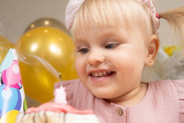 İki yaşında bir kız doğum günü pastasına mum üflüyor ve bir dilek diliyor..