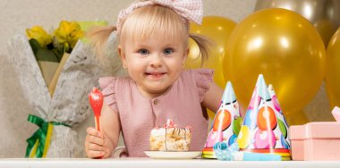 Doğum gününde pasta yiyen iki yaşında sarışın bir kız.