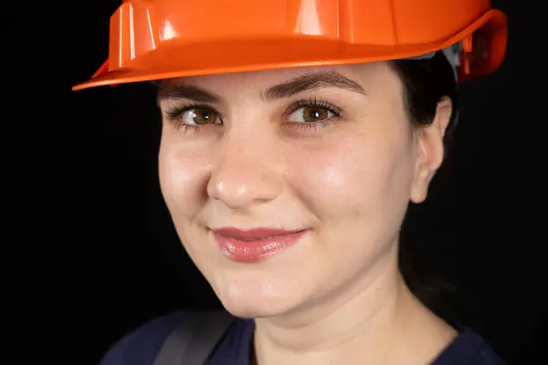 A female construction worker or engineer wearing a protective orange mask on a black background.