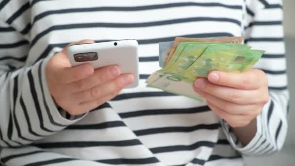 女性が手元にユーロの請求書を持ち スマートフォンを使用する — ストック動画