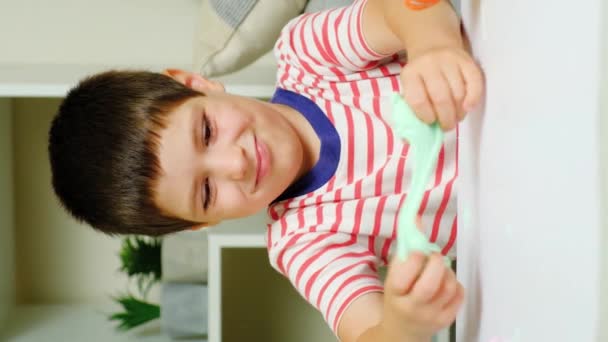 一个六岁的男孩坐在家里的桌子旁玩黏液游戏 儿童玩具一种用于培养儿童优秀运动技能和创造力的玩具 — 图库视频影像