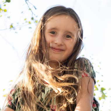 Rüzgarda dalgalı uzun saçları olan 5-6 yaşlarında bir kızın portresi..