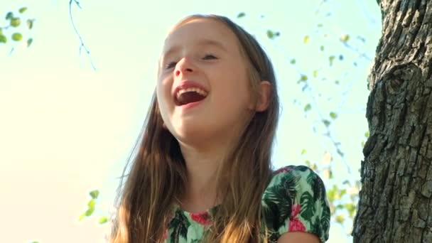 夏に木の上に座っている笑うかわいい女の子の肖像画 — ストック動画