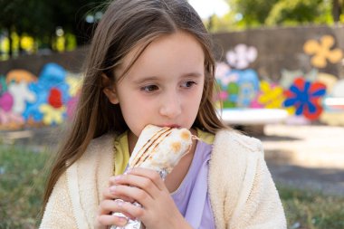 Açık havada Pita ekmeği içinde shawarma yiyen güzel bir kız. Sokak yemeği.