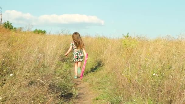 小さな女の子は彼女の手で体操フープと夏のフィールドを横切って走ります — ストック動画